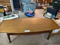 Front angled view of the coffee table showing shape, tapered legs, and lower shelf.
