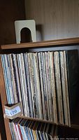 Side view of a shelf densely packed with vinyl records mostly from the 1960s and 1970s, showing a large collection.