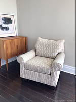 Side angled view of the Barrymore accent chair showing geometric upholstery fabric, rolled sock arm and solid dark wood base on wood floor.