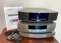 Stacked view of two Bose Wave systems with manual on wooden surface