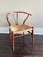 Front angle of the mahogany wishbone chair showing the paper cord seat and gently curved backrest design.