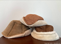 Three vintage women's bucket hats: two shearling leather and one ultrasuede. Positioned on a flat surface against a plain background, showing side and top angles.