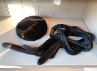 Photo of the dark brown mink tam/beret and two long matching mink scarves laid out on a white surface showing the texture and color of the fur.