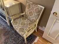 Front and angled view of the antique Bergere chair showing damask upholstery and cream wooden frame with wear.