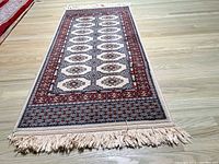 Full view of the runner rug laid flat showing the Bokhara design, color pattern and fringes.