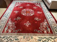Full view of red field, central medallion, border and fringe near seating area