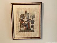 Frontal view of framed Egyptian papyrus painting showing two figures and decorative symbols in vibrant colors.
