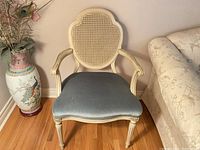 Front view of chair showing cane back, curved arms, blue velvet seat and white frame