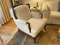 Front left angle full view of armchair showing walnut frame, upholstery and floor covering