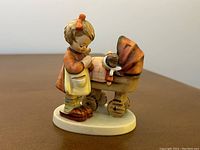 Front view of the figurine showing the girl beside the baby carriage holding a doll.