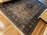 Full view of rug on hardwood floor showing central medallion and border.