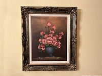 Front view of painting showing pink roses in blue vase and ornate gilt frame