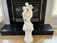 Full front view of white lovers statue on column pedestal placed on hearth
