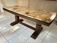 Side angle showing the large rectangular marble top with opus pattern and solid wood base with detailed carvings.