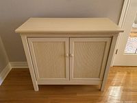 Front view of white wood cabinet with two reeded doors and round knobs