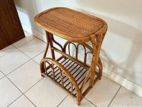 Side angle showing woven rattan tabletop and curved frame with integrated lower magazine rack