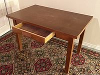 Side view of wooden work table showing open drawer and top surface