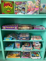 Shelves holding a variety of board games and puzzles boxed sets showing titles, colorful box art, and varied sizes.