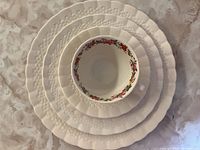 Stacked set of bone china plates and a tea cup showing size gradation and embossed edges