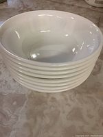 Stack of eight white bowls showing smooth interior and shape.
