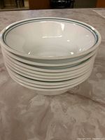 Stack of eight white bowls with green double stripe rim pattern