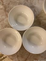 Top view showing three white serving bowls grouped together on marble surface.