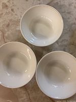 Top-down view of three white Corelle serving bowls arranged in a triangular pattern.
