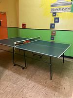 Ping pong table set up with paddles and ball on the table, showing overall condition and setup