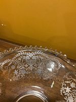 Close-up of glass serving bowl showing intricate silver floral inlay and decorative bubble edge