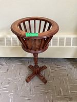 Front angle view of wooden plant stand showing basket, column, and base.