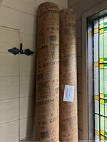 Three Ecoform Sono Tubes of different lengths standing upright by a stained glass window, showing printed brand and size information.