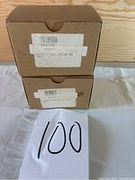 Two cardboard boxes labeled as exhaust fan motors stacked on each other with a paper showing lot number 100