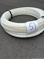 Full coil of white PEX tubing approximately 40 feet long, coiled and secured with ties, placed on pavement.