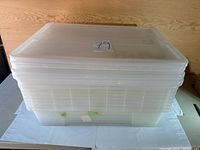 Stacked eight clear plastic storage totes with lids visible, clear translucent plastic, rectangular shape, no cracks