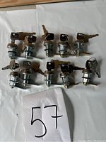 Ten metal cam locks each with a pair of keys laid out on a white surface.