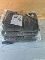 Stack of ten folded Propper women's tactical pants in plastic packaging, grey color, size 8.