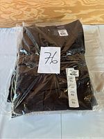 Five pairs of folded men's tactical pants in plastic bags, labeled with size and brand tags visible.