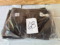 Sealed package containing folded grey tactical pants with lot number label.