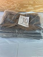Stack of five grey women's tactical pants in plastic packaging with a '90' label on top.