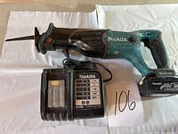 Full view of Makita cordless reciprocating saw with attached battery and charger on a white background.