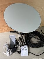 Satellite dish with tripod, cables, power adapters, and router assembled and shown from front view