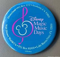 Photo of the front of the blue 3 inch Disney Magic Music Days vintage pinback button showing logo and promotional text for Anaheim, CA and Lake Buena Vista, FL locations.