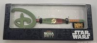 Photo of the exclusive collector key inside its black display box, showing the green Disney logo handle and Star Wars The Book of Boba Fett branding.