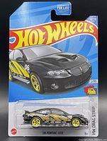 Front view of unopened Hot Wheels packaging featuring the '06 Pontiac GTO model car in black with yellow racing decals and wheels.