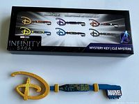 Collector's key in new open box condition with gold Disney 'D' logo bow, blue handle featuring Groot and 'We Are Groot' text, and 'MARVEL' blade end.