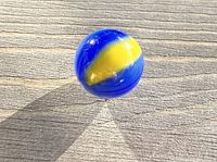 Top view of a handmade glass marble showing blue and yellow swirl design.