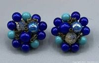 Pair of vintage clip-on earrings with clusters of shiny blue beads in various shades forming a spherical shape.