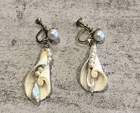 Front view of one earring showing seashell pendant with faux pearls, screw back clip and large pearl at top