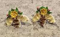 Front angled view of the pair of earrings showing the yellow flower center, seashell petals with brown stripes, green leaves, and pink buds.