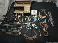 Full view of assorted vintage costume jewelry pieces including watches, necklaces, bracelets, brooches, and a jewelry box.